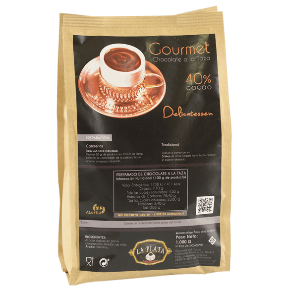 Taza blanca esmaltada rellena de chocolate caliente oscuro y espeso, decorada con una ramita de canela sumergida y gotas de chocolate derramadas por el borde exterior. Alrededor, sobre una superficie de madera oscura, se disponen rodajas de naranja deshidratada, una de ellas parcialmente cubierta de chocolate, y varias ramas de canela. Una imagen cálida y aromática que evoca el sabor tradicional con un toque cítrico y especiado.